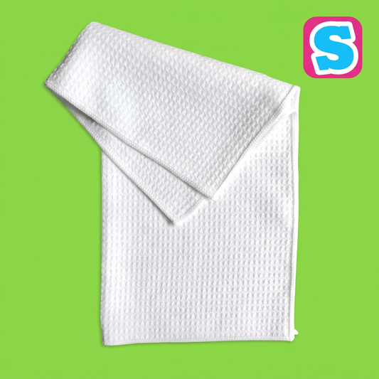 White waffle weave sublimation tea towel on a green background with Sublimania S logo