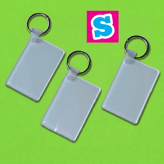 Three rectangular acrylic sublimation keyrings with metal split rings on a green background with Sublimania S logo
